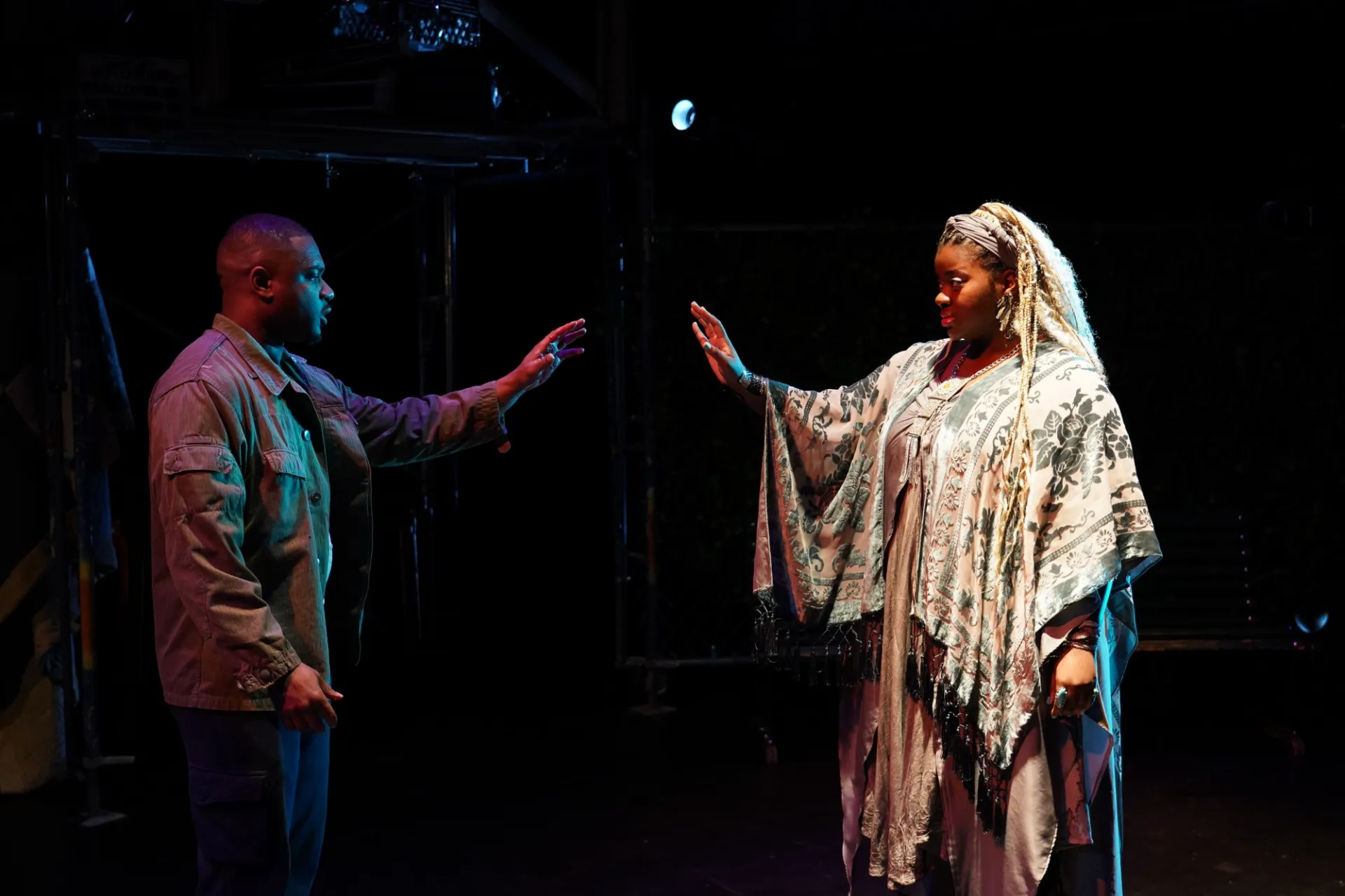 Two actors on stage reach towards one another
