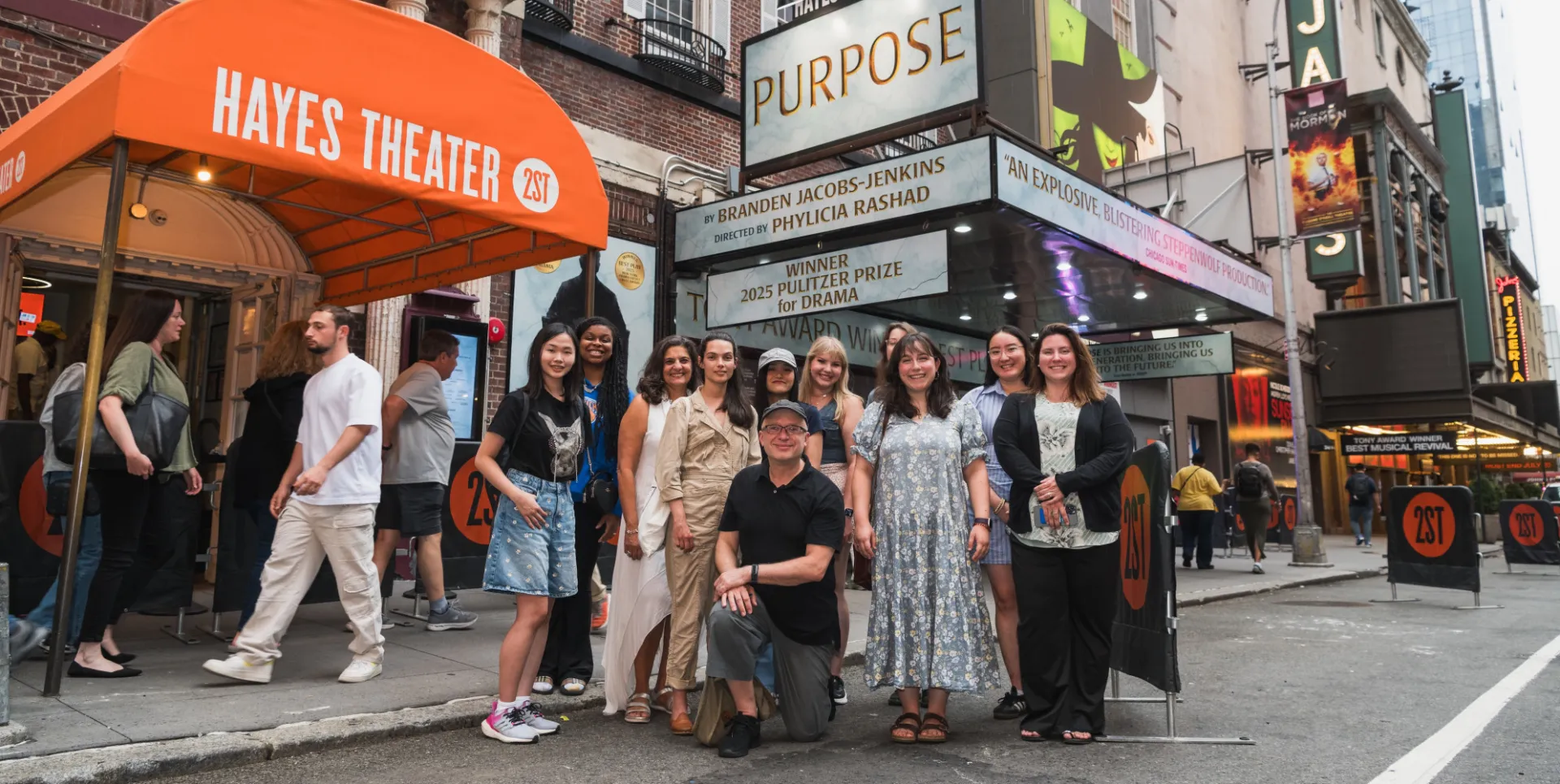 a group of people stand in front of a theatre marquee