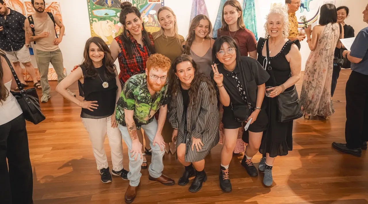 a group of students pose together for a photo in an art gallery