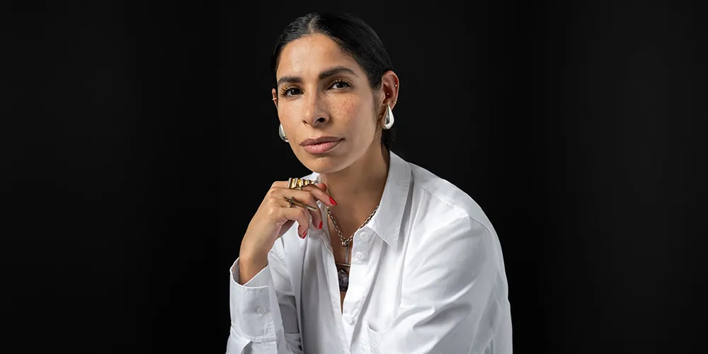 writer Jessica Hoppe wearing a white button shirt in front of a black background