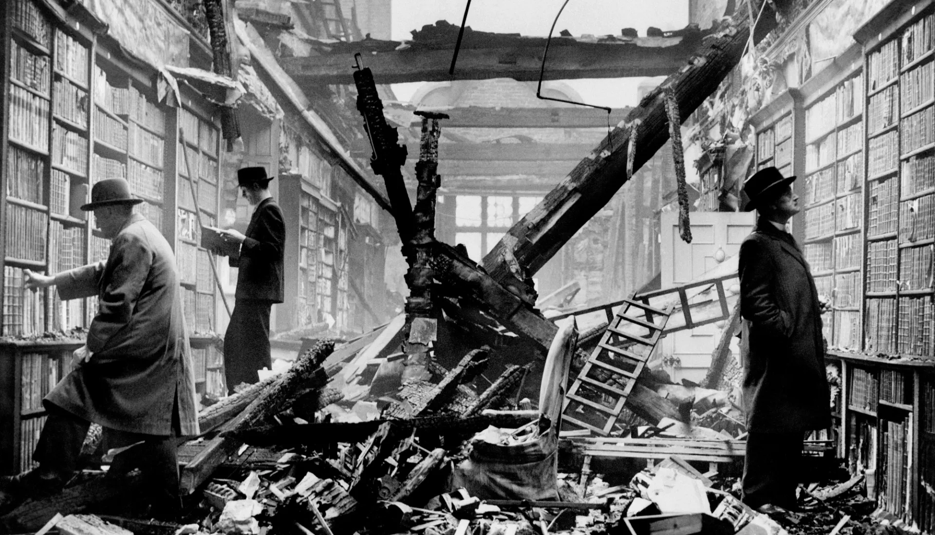 Three people explore a partially damaged library.