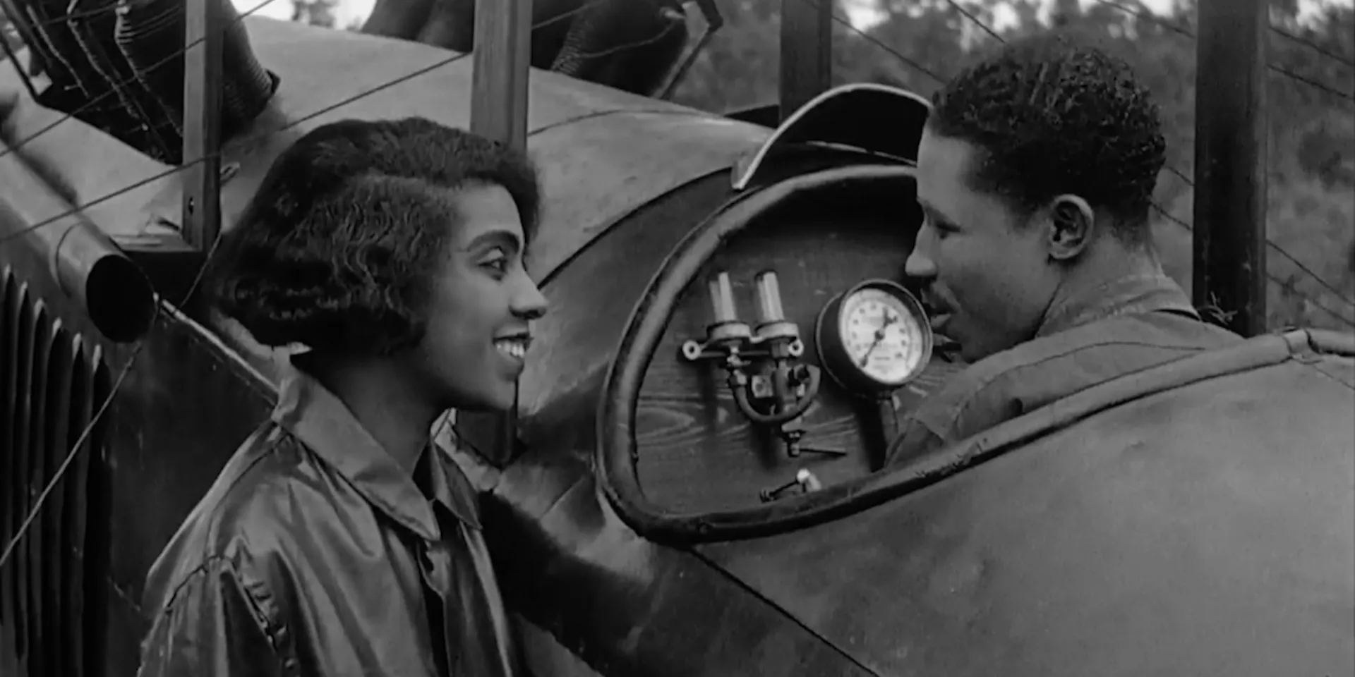 a woman speaks to a man sitting in a small aircraft