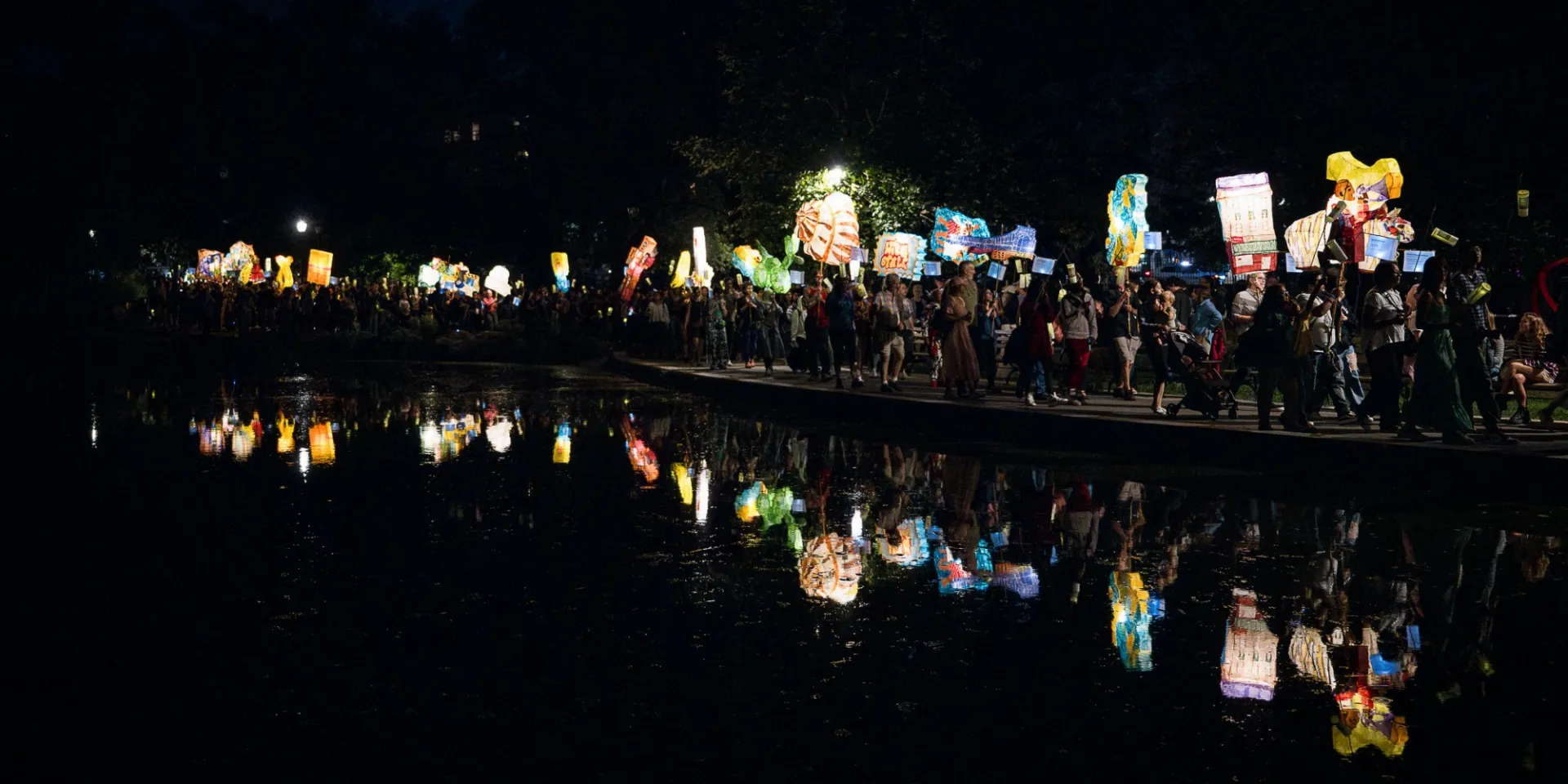 a procession of people walk with lanterns at nighttime