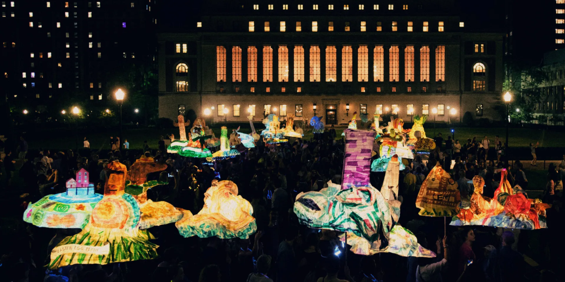 People carry paper lanterns outside at night.