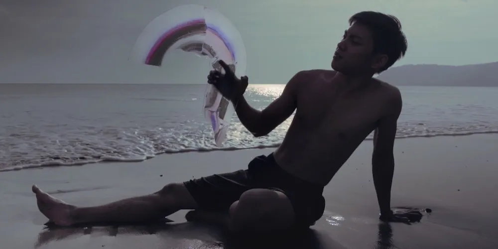 a person holds an abstract shape on a beach