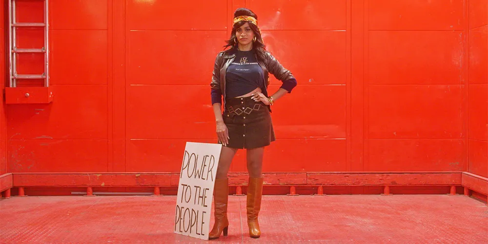 woman standing in red room with sign that says power to the people