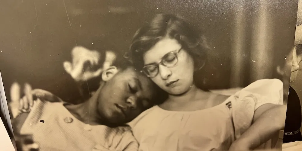 two girls sit together, leaning their heads against one another
