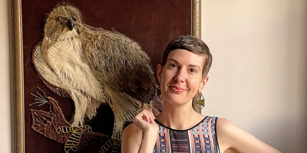 woman with short hair standing with owl painting