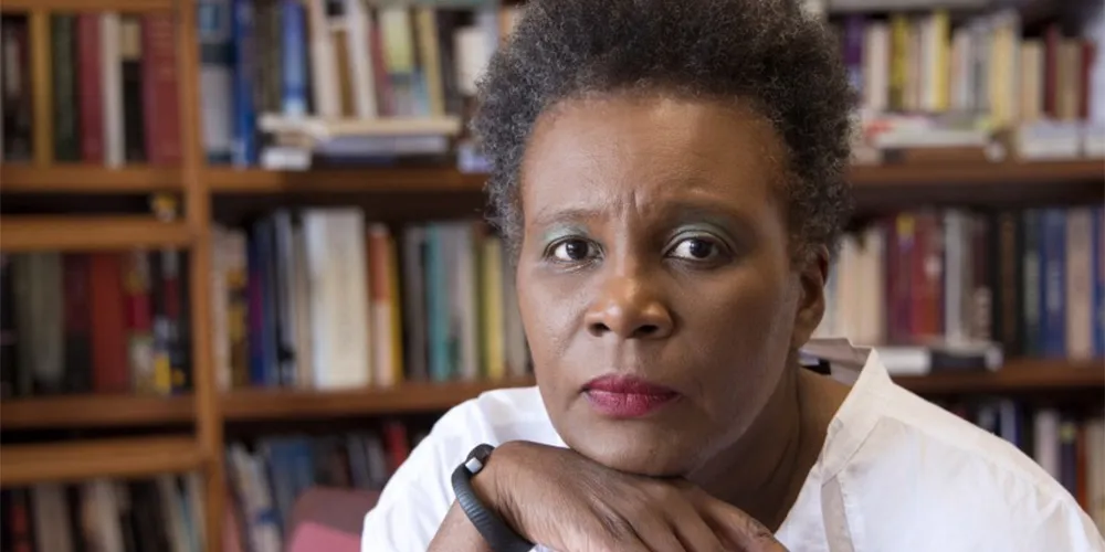 claudia rankine sitting in front of bookshelf