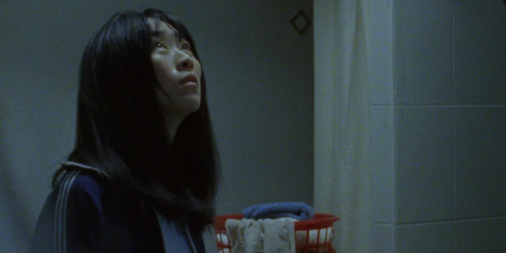 woman in a dimly lit bathroom looks up