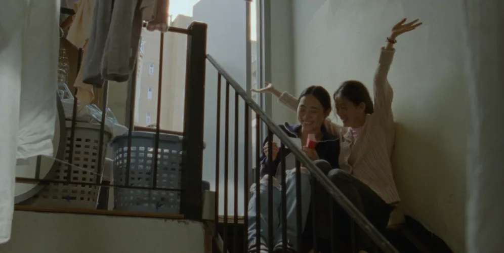 Two women sitting on stairwell laughing together. 
