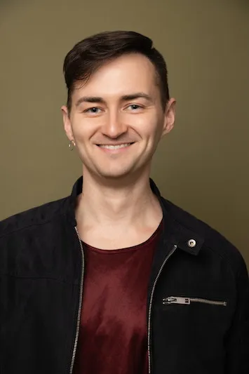 Profile photo of Calvin Atkinson wearing a burgundy T-Shirt and black jacket, smiling.