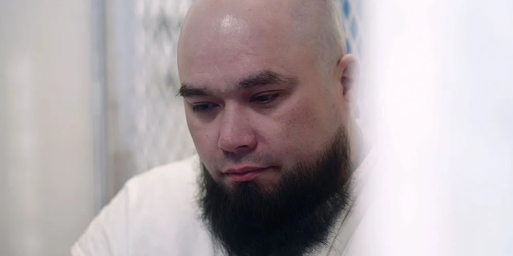 Man with shaved head and beard looks melancholy. 