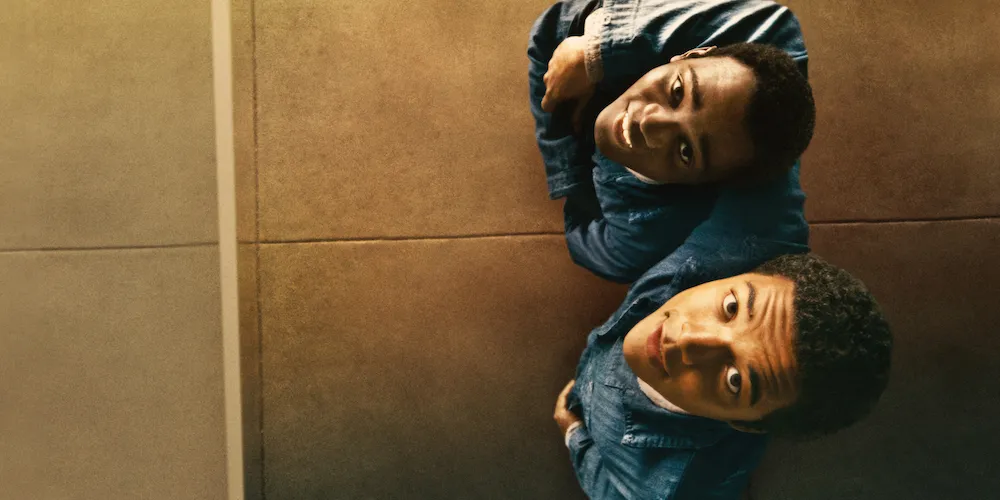Tow young men look upwards into the camera. 