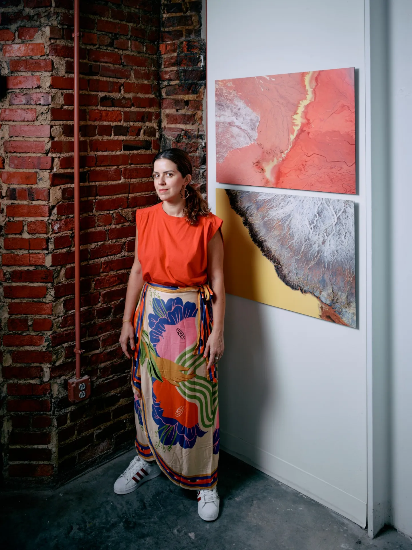 Artist stands in front of artworks. 