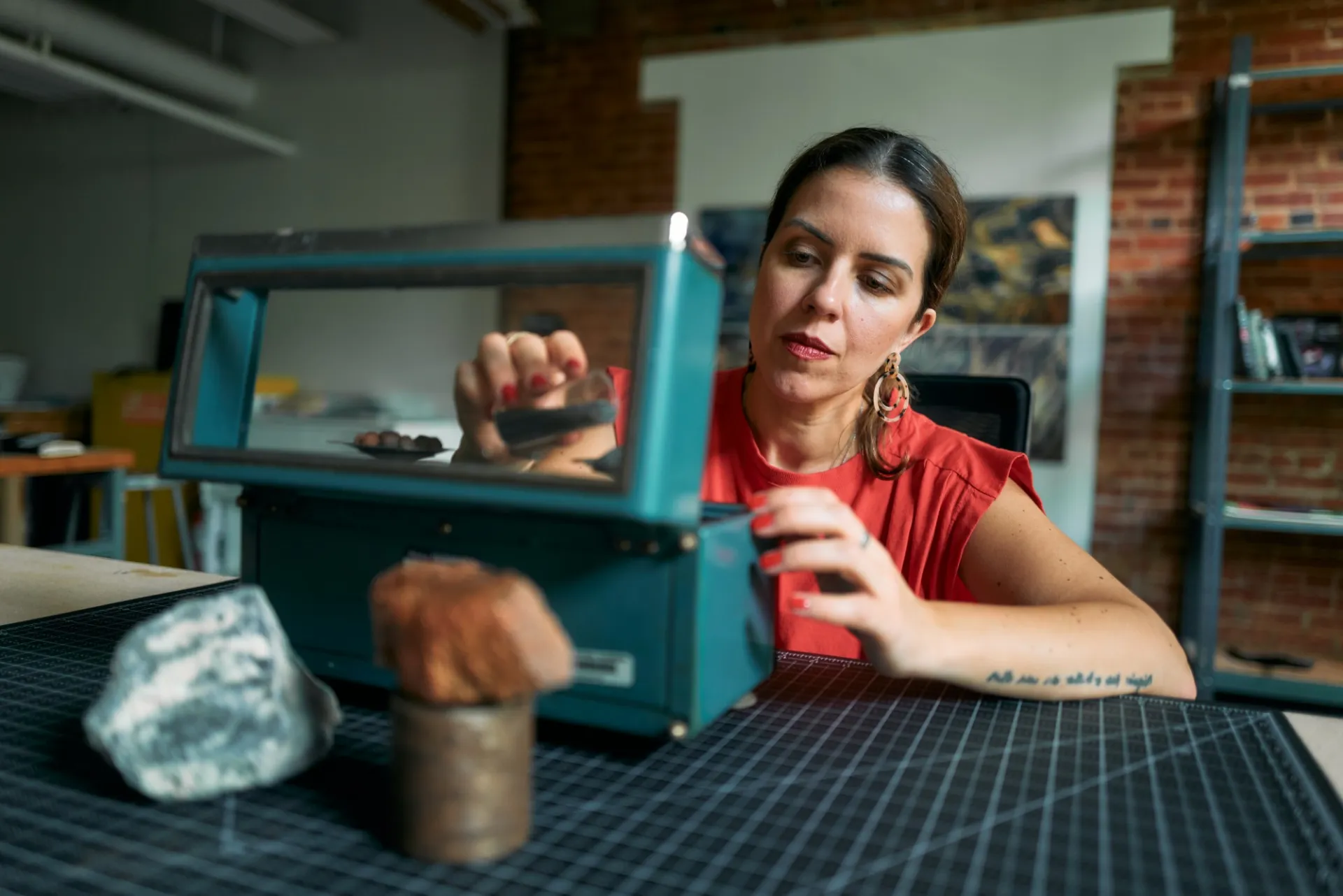 Artist examines objects on a table. 