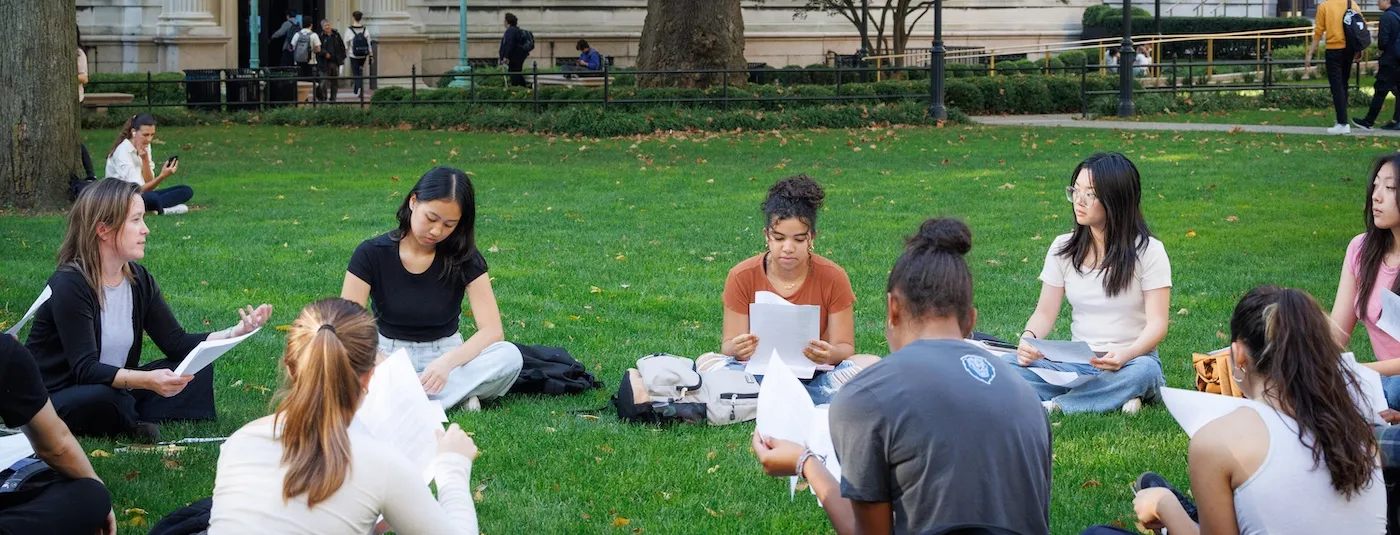 a group of students meet for class outside on the lawn