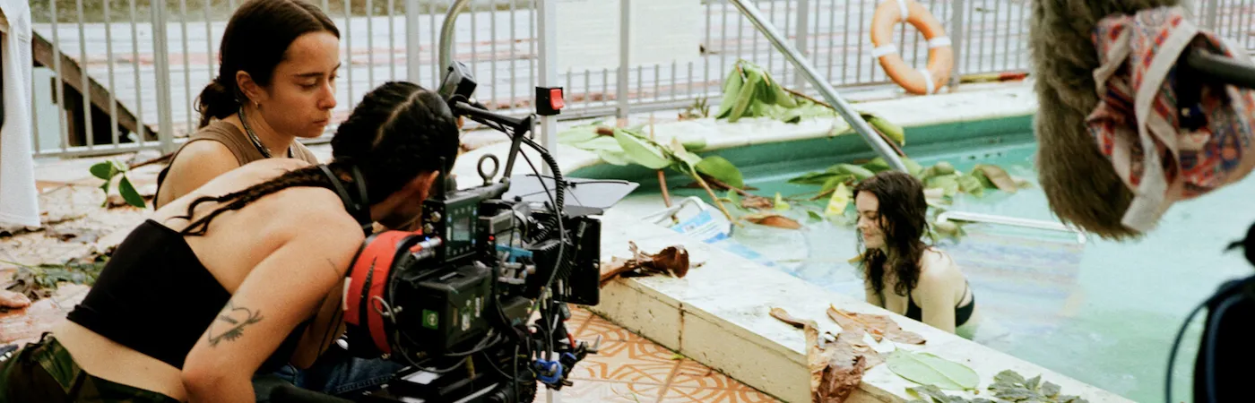 A film crew films a scene outside near a pool.