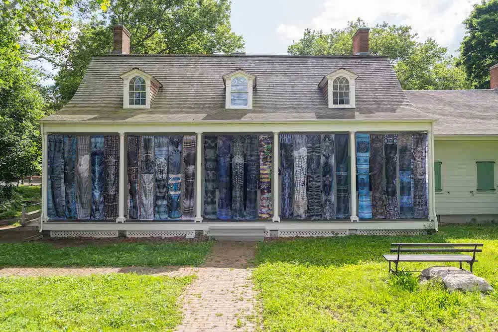 House with long banners with blue designs hanging in between six white columns.