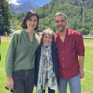 Three people stand near mountains