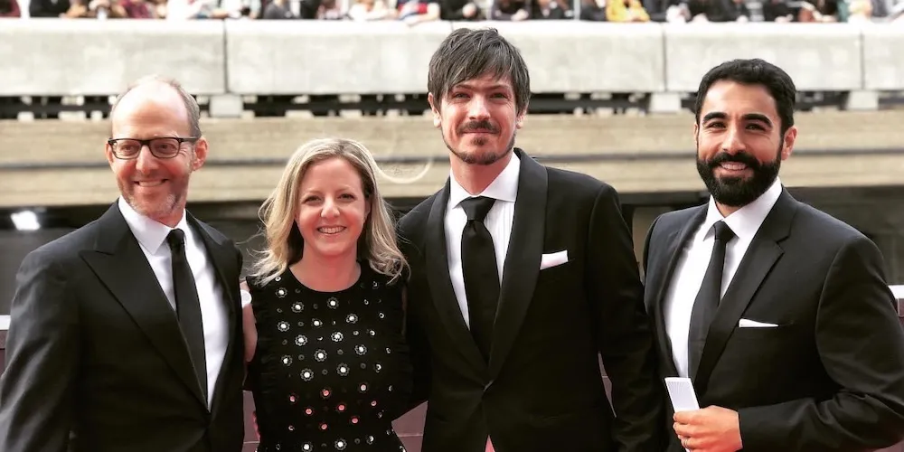 Four people pose in fancy clothes at an awards ceremony