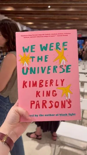 hand holding up book: We Were the Universe