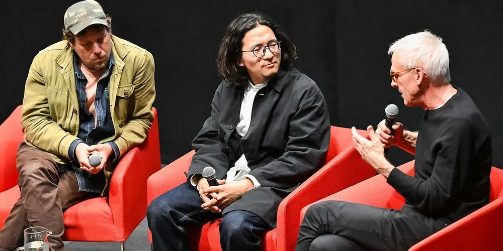 three people sitting in red chairs have a discussion