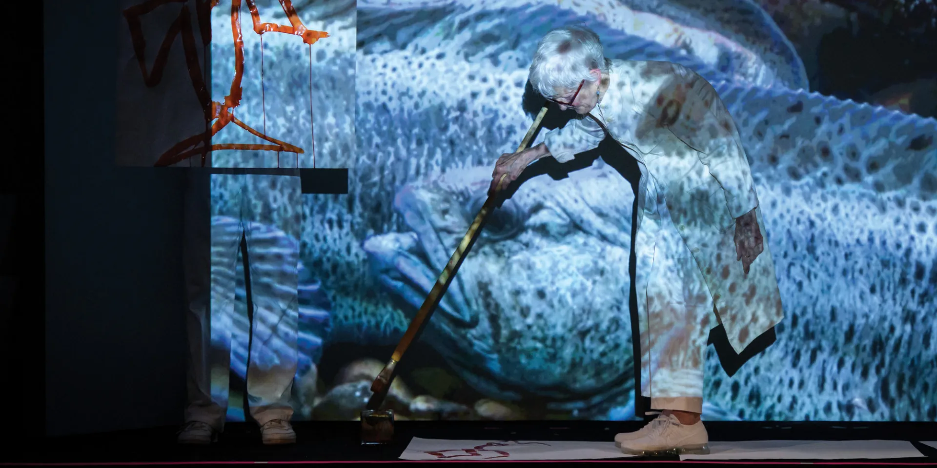 A woman paints on a canvas laid on the ground