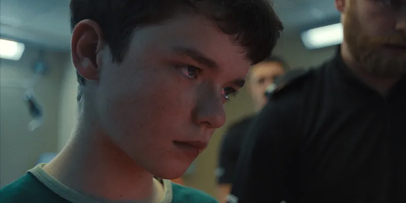 A young boy looks ahead with a skeptical expression. 