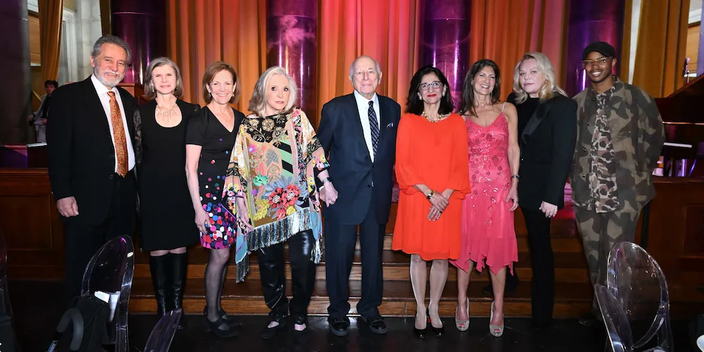 9 people pose in front of a stage