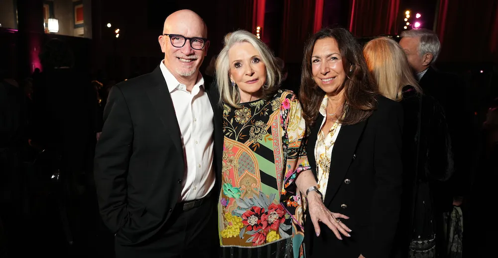 3 people pose in a darkened ballroom