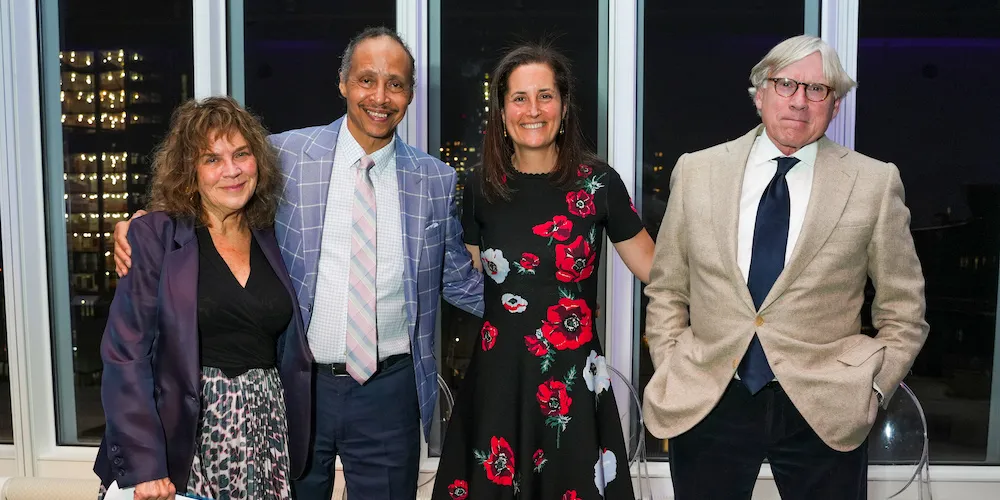 Four people pose for a photo on a stage. 