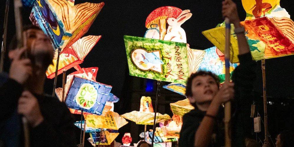 A crowd of people carring glowing lanterns