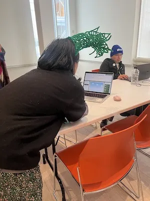 a person wearing a hat works at a laptop