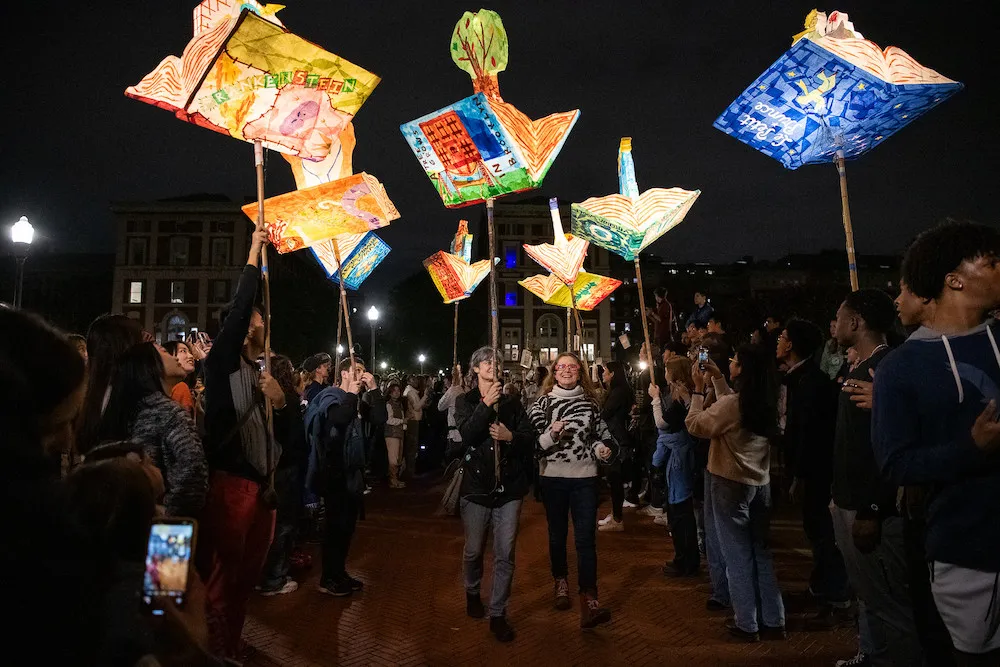 Procession of people bearing glowing lanterns of different books