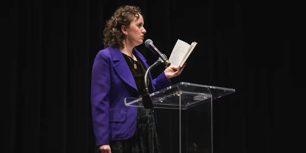 an author reads from a book at a podium