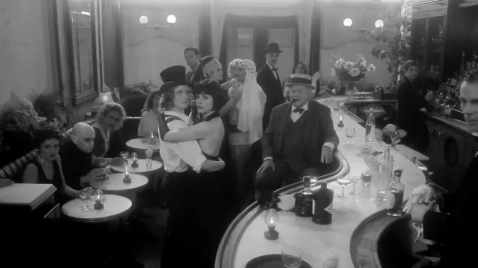 Black and white film scene of a crowd in a bar
