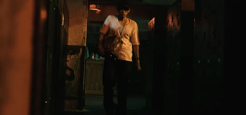Person in dimly lit building holding a valise