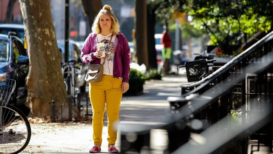 A woman stands on a sidewalk.