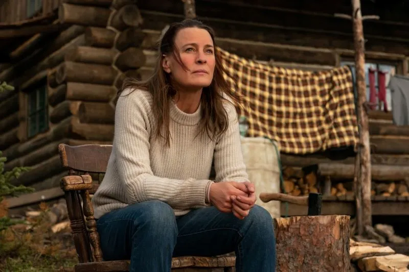 Woman seated in wooden chair outside a logcabin