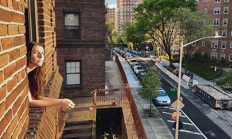 Woman looking out window on a city block