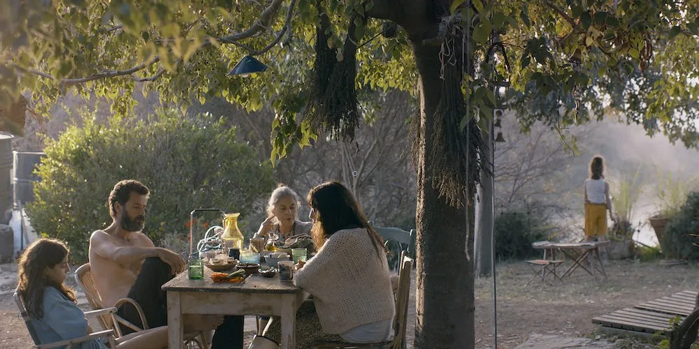 People seated outside at a table under a tree