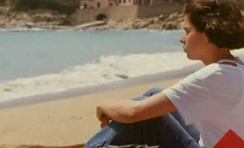 A woman sits at the beach.