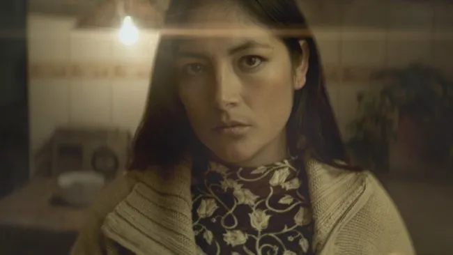 Dark haired women in traditional Andean stress gazing at the camera