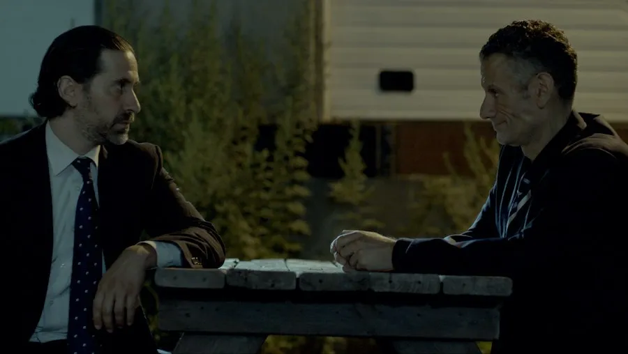 two seated men talking at bench table