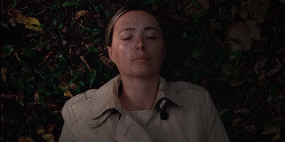 Character in trench coat lying in foliage