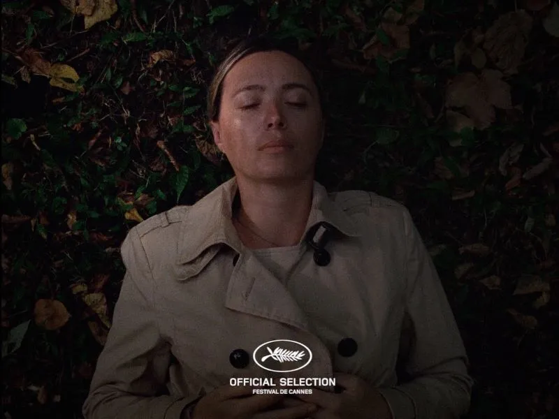 Person in trench coat lying down in grass