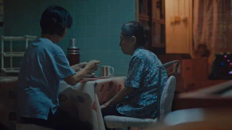 Two people seated at a kitchen table in the dark