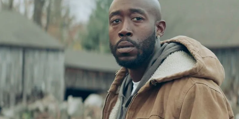 Man in tan jacket looking ahead sadly