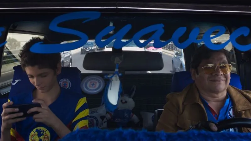 Man and boy wearing blue in car as viewed through windshield 